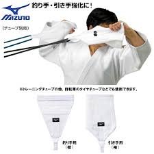 Atleta de judo entrenando kumi-kata con agarres de solapa y manga Mizuno conectados a bandas elásticas para fortalecimiento de tsurite y hikite.