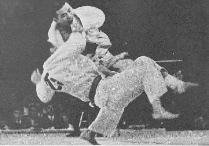 Fotografía histórica en blanco y negro del maestro Isao Okano ejecutando una proyección elevada en el tatami