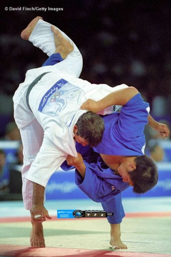 Kosei Inoue ejecutando una proyección de Uchi-mata con el dorsal oficial de los Juegos Olímpicos de Sídney 2000.