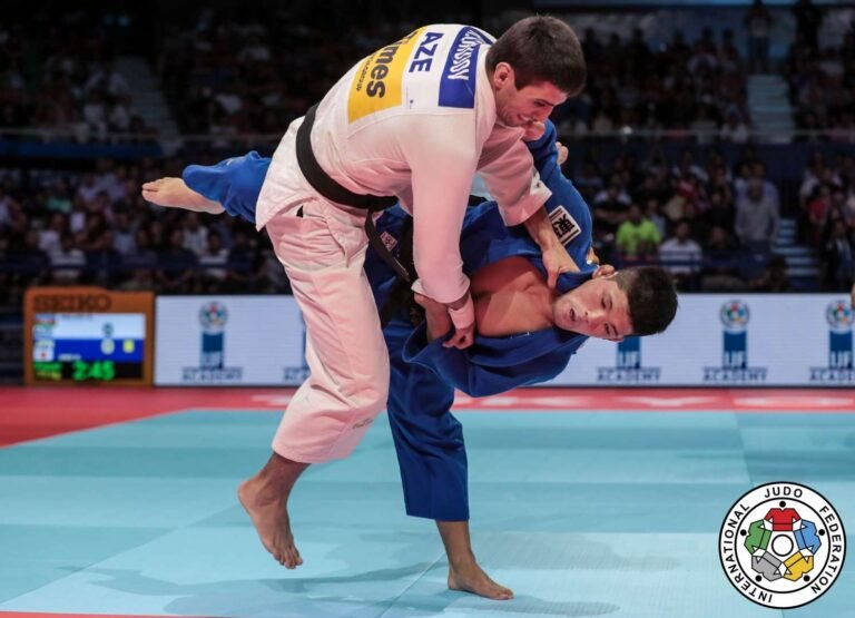Judoka realizando una técnica de barrido de pierna durante un combate de alto rendimiento en el tatami.