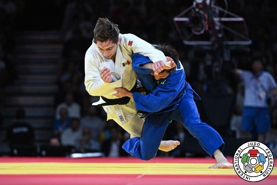El judoka Hifumi Abe con judogi azul desequilibrando firmemente a Denis Vieru con judogi blanco durante los Juegos Olímpicos de París 2024.