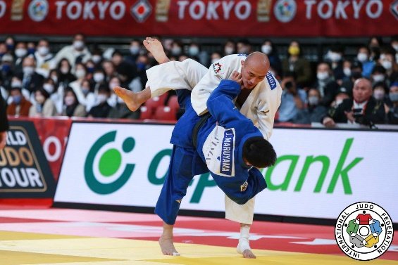 El judoka Joshiro Maruyama con judogi azul ejecutando una proyección aérea alta contra un oponente con judogi blanco durante el Grand Slam de Tokio