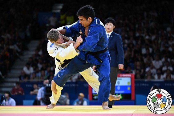 El judoka Takanori Nagase con judogi azul disputando firmemente el kumi-kata frente a Matthias Casse durante un torneo oficial.