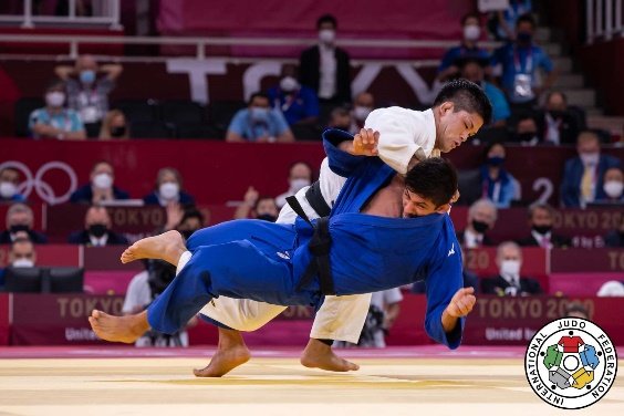 El judoka Shohei Ono con judogi blanco ejecutando un lanzamiento dinámico sobre un oponente con judogi azul durante los Juegos Olímpicos de Tokio 2020.