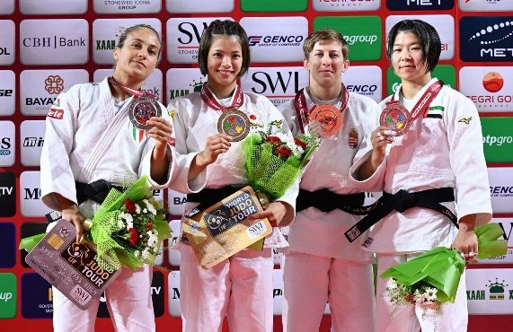 La judoka japonesa Uta Abe en el centro del podio sosteniendo su medalla de oro y un ramo de flores junto a las demás medallistas de la categoría -52 kg.
