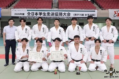 El equipo masculino de judo de la Universidad de Teikyo posando con diplomas y un trofeo pequeño sobre el tatami del Nippon Budokan.