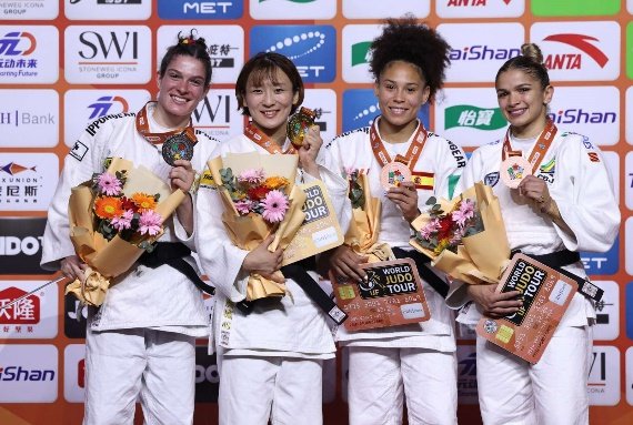 La judoka japonesa Natsumi Tsunoda en el centro del podio sosteniendo su medalla de oro y un ramo de flores junto a las medallistas de Alemania, España y Brasil.