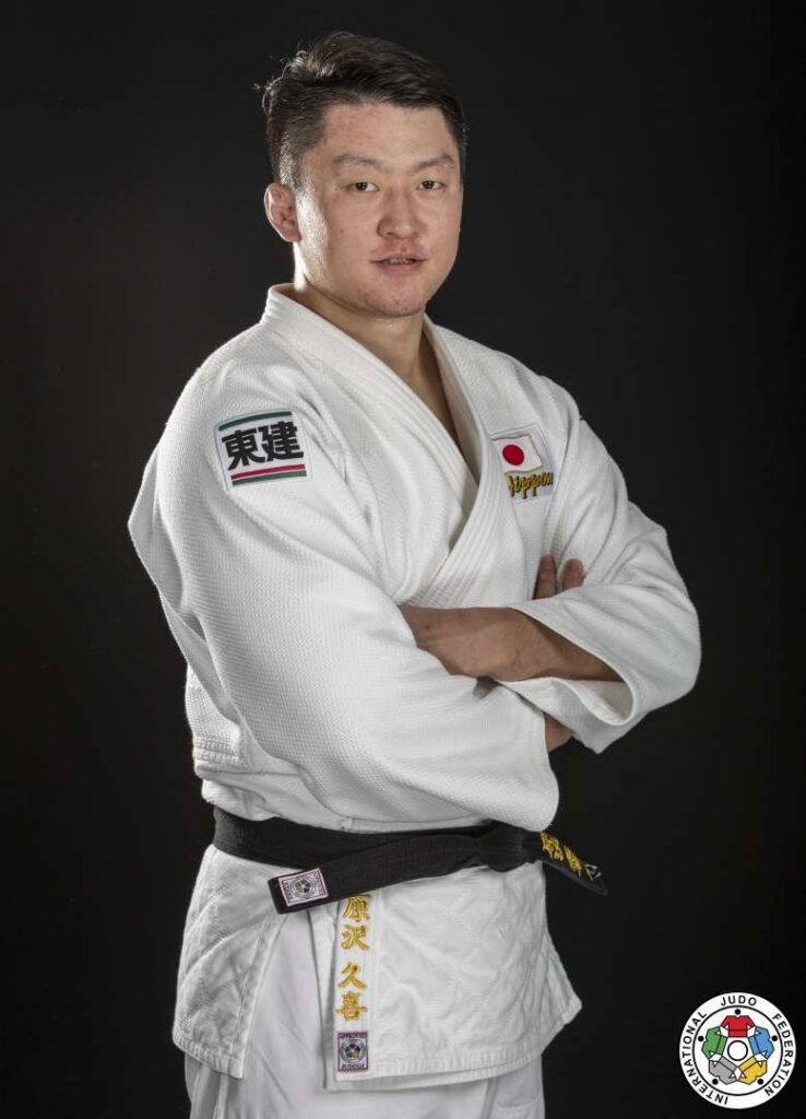 Retrato oficial en plano medio del judoka japonés Hisayoshi Harasawa posando con brazos cruzados, judogi blanco, parche de Japón y cinturón negro de la IJF.