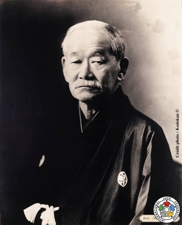 Retrato oficial en blanco y negro del maestro Jigoro Kano de mayor, vistiendo kimono oscuro tradicional japonés.