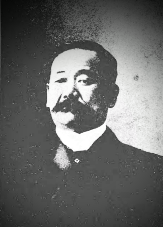 Retrato en blanco y negro de Jigoro Kano de adulto con bigote prominente y traje occidental formal.
